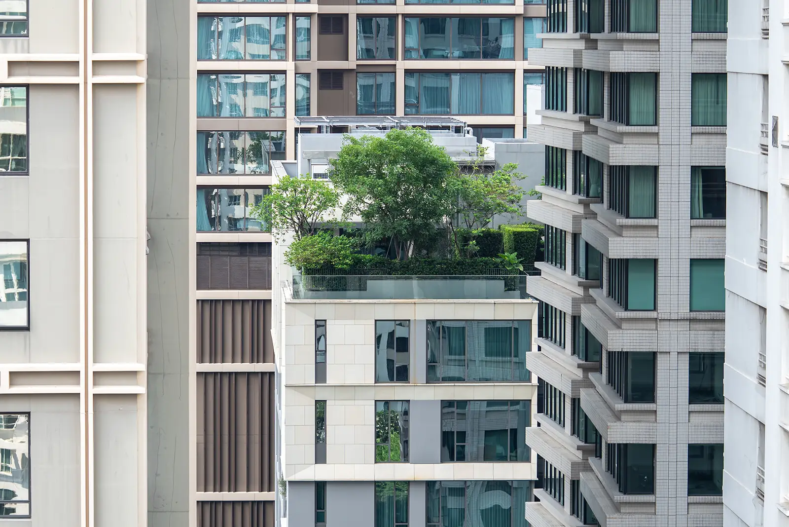 Modern high-rise buildings in urban Bangkok, Thailand, featuring a lush rooftop garden. Exemplifies Citadel Real Estate.