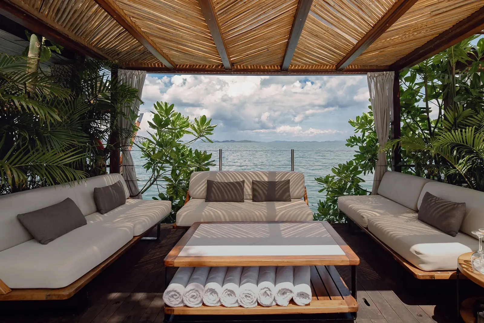 Luxurious floating lounge at Yona Beach Club, featuring white sofas, wooden table, and tropical ocean views.